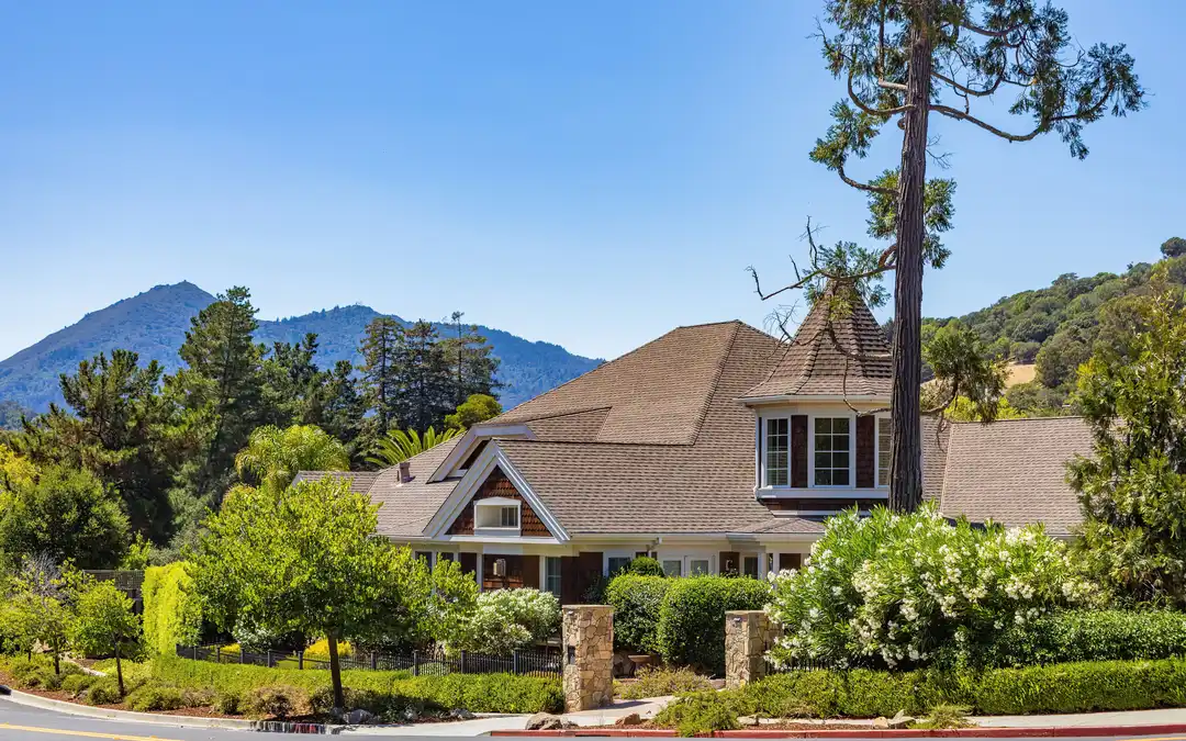 A craftsman-style home surrounded by greenery below the mountains